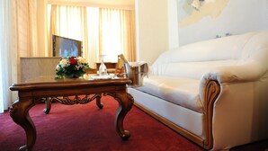 Ein Zimmer mit rotem Teppich, einem weißen Sofa, einem Holztisch mit Blumen und einem Bild an der Wand.