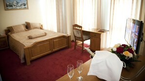 Ein Hotelzimmer mit Bett, Schreibtisch, Stuhl, Fernseher und einer Blumenkomposition.