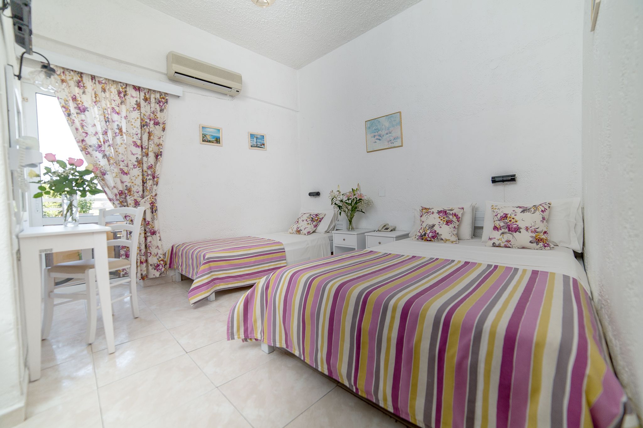 A bedroom with two beds, a desk, and a chair.