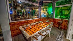 A foosball table in a room with brick walls and large windows. - Roxani Hotel (Malevizi)