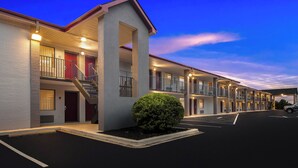 Een motel met meerdere verdiepingen, een centrale trap en een goed verlichte gevel.