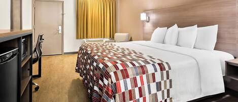 Una habitación de hotel con una cama grande, un escritorio, una silla y un armario.