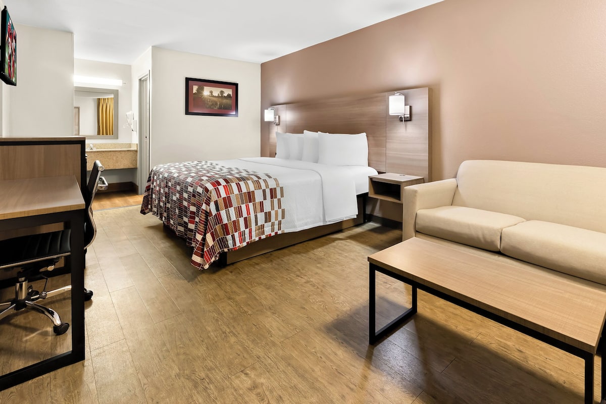 Een hotelkamer met een bed, een bureau, een stoel, een bank en een nachtkastje.
