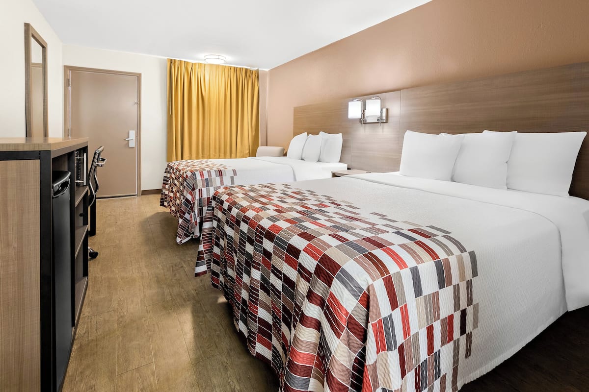 Een hotelkamer met twee bedden, een bureau en een kledingkast.