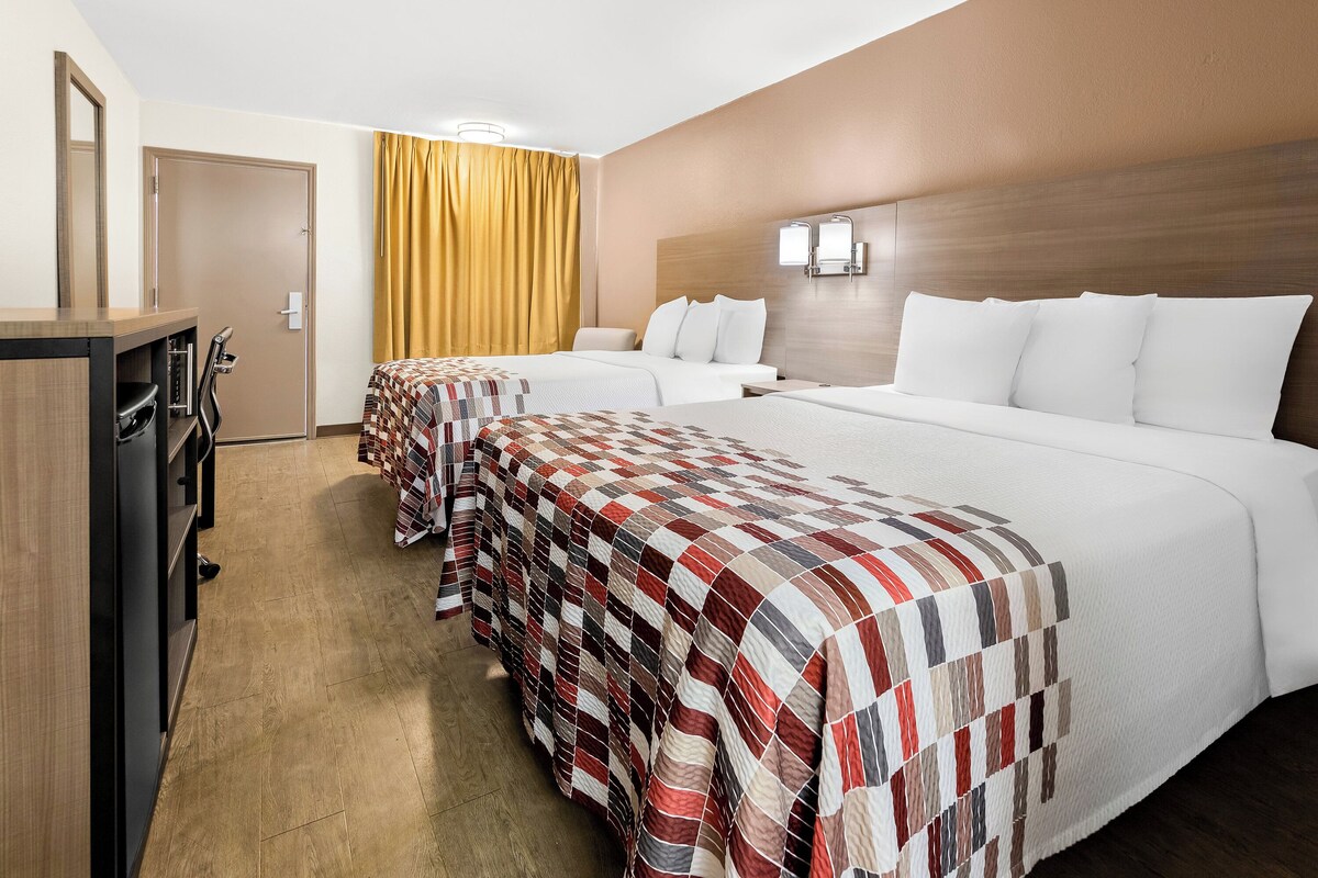 Une chambre d’hôtel avec deux lits, un bureau et une armoire.