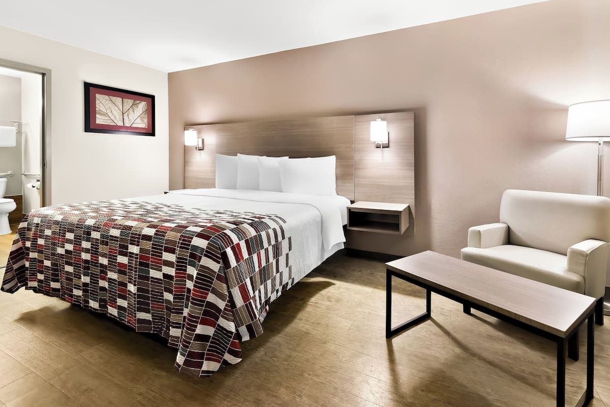 Een hotelkamer met een bed, nachtkastje, stoel en een tafel.