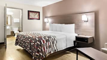 A hotel room with a bed, bedside table, and a view of the bathroom.