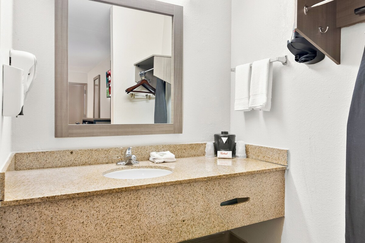 A bathroom with a granite countertop, a sink, a mirror, a towel rack, and a towel hanging on the wall.