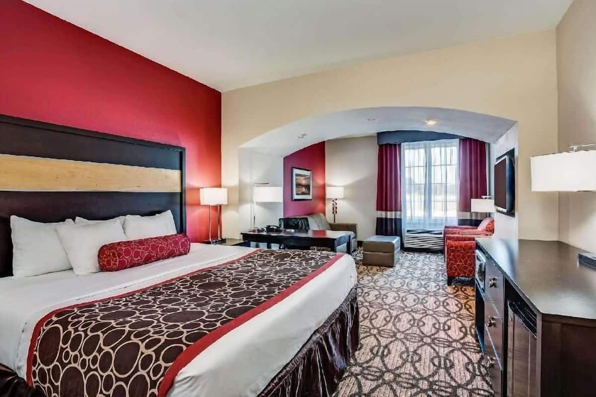 A hotel room with a large bed, a desk, a chair, and a TV.