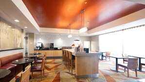 A modern hotel lobby with a bar area, seating arrangements, and a patterned carpet.