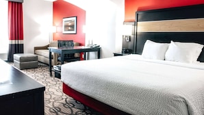 A hotel room with a large bed, a desk, a chair, and a sofa.