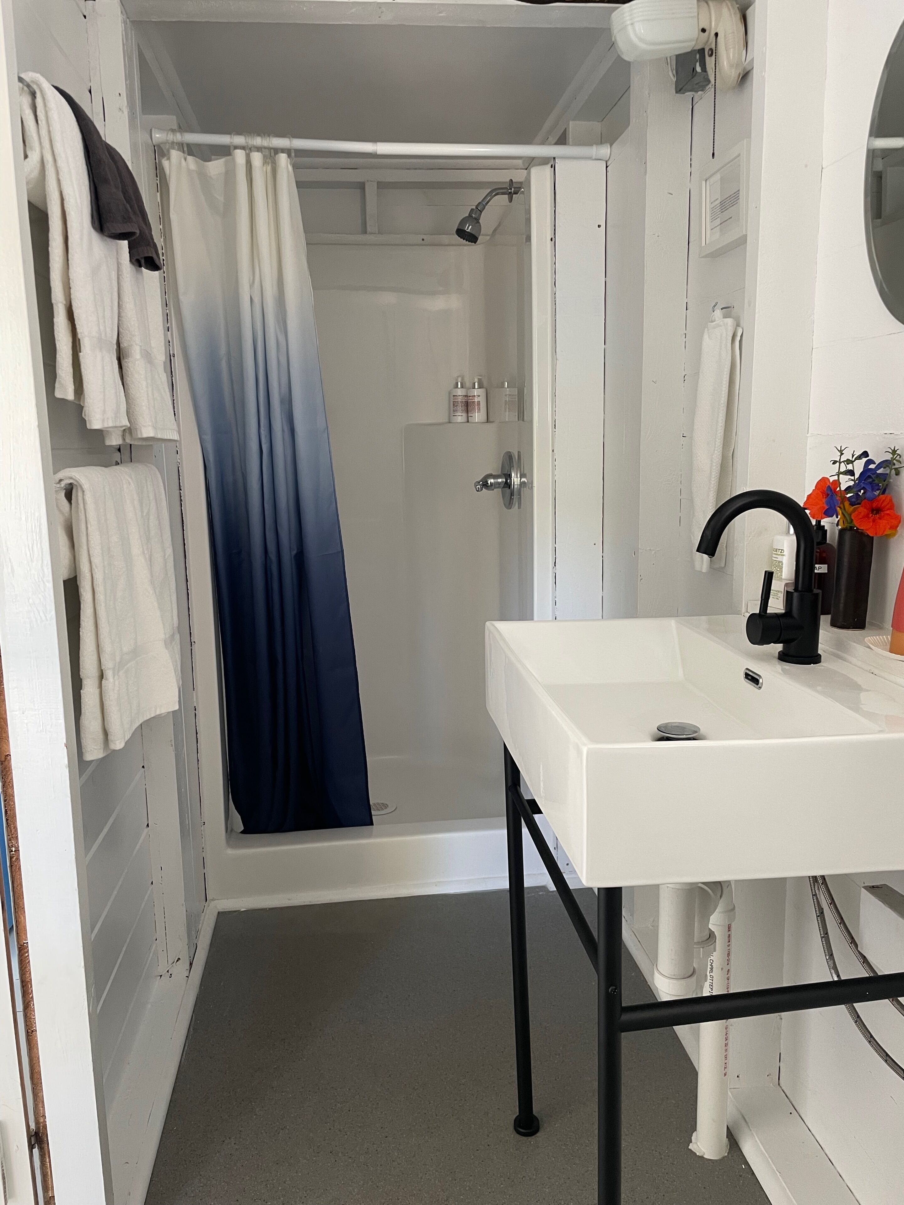Un baño con lavamanos blanco, cortina de ducha y barra para toallas.
