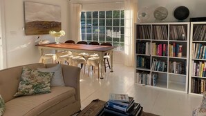 Una sala de estar con sofá, una mesa de comedor, una estantería y una ventana con vistas al exterior.