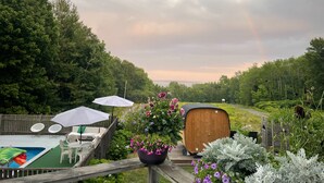 A wooden deck with outdoor furniture, a pool, and a view of a forested area. - Lincolnville Motel (Lincolnville)