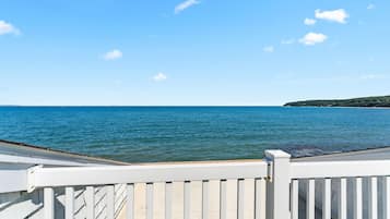 A view from a balcony overlooking a calm sea with a clear sky.