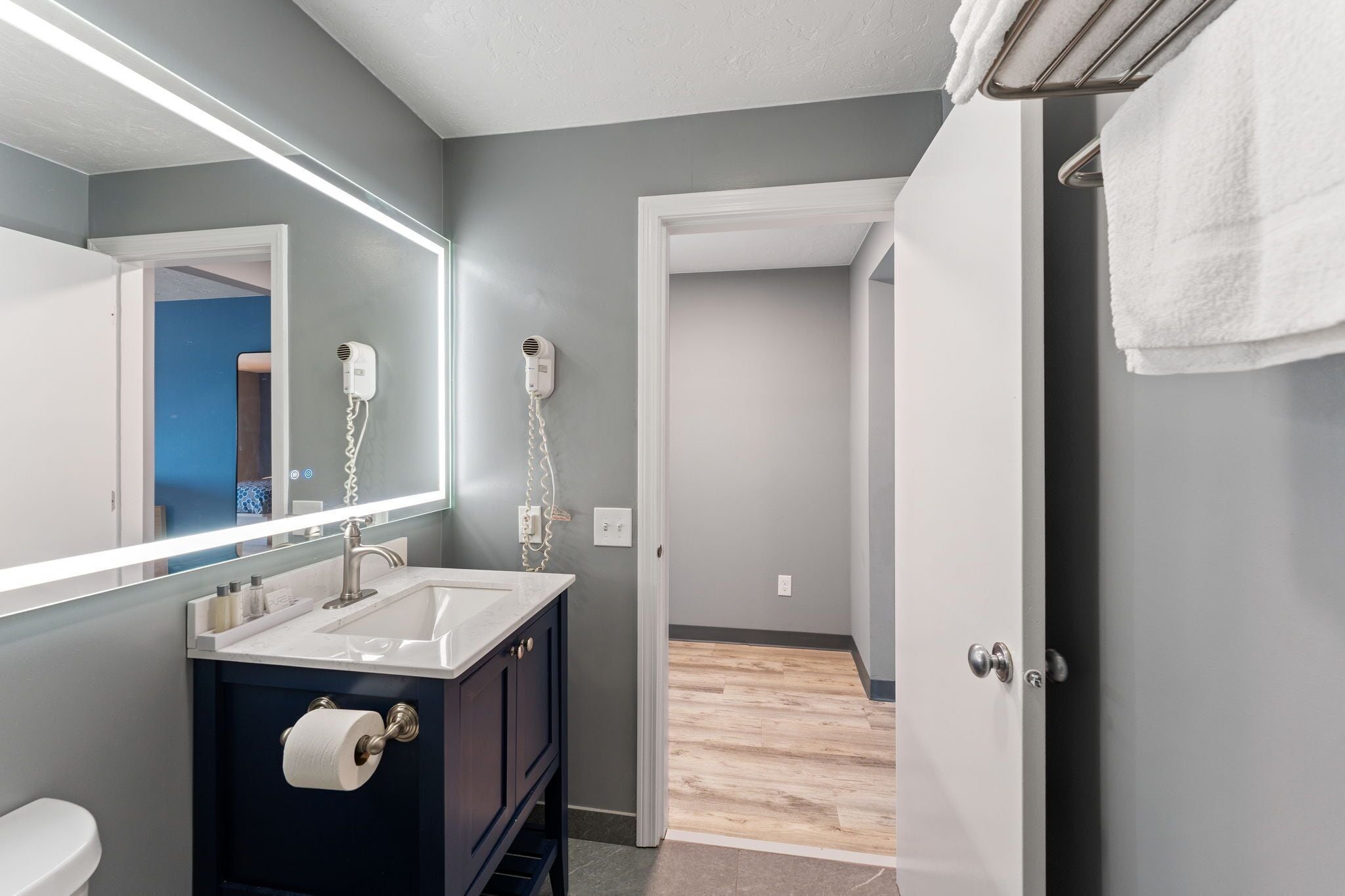 A modern bathroom with a large mirror, a sink, and a hairdryer.