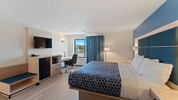 Una habitación de hotel moderna con cama, escritorio, silla y televisor montado en la pared.