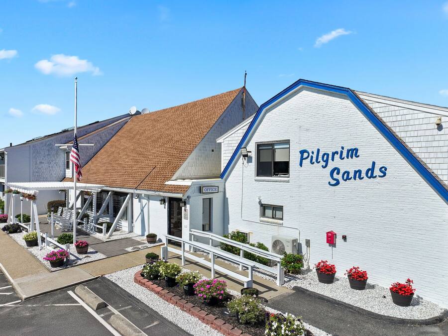 Um edifício com fachada branca e detalhes azuis, com a placa 'Pilgrim Sands'.