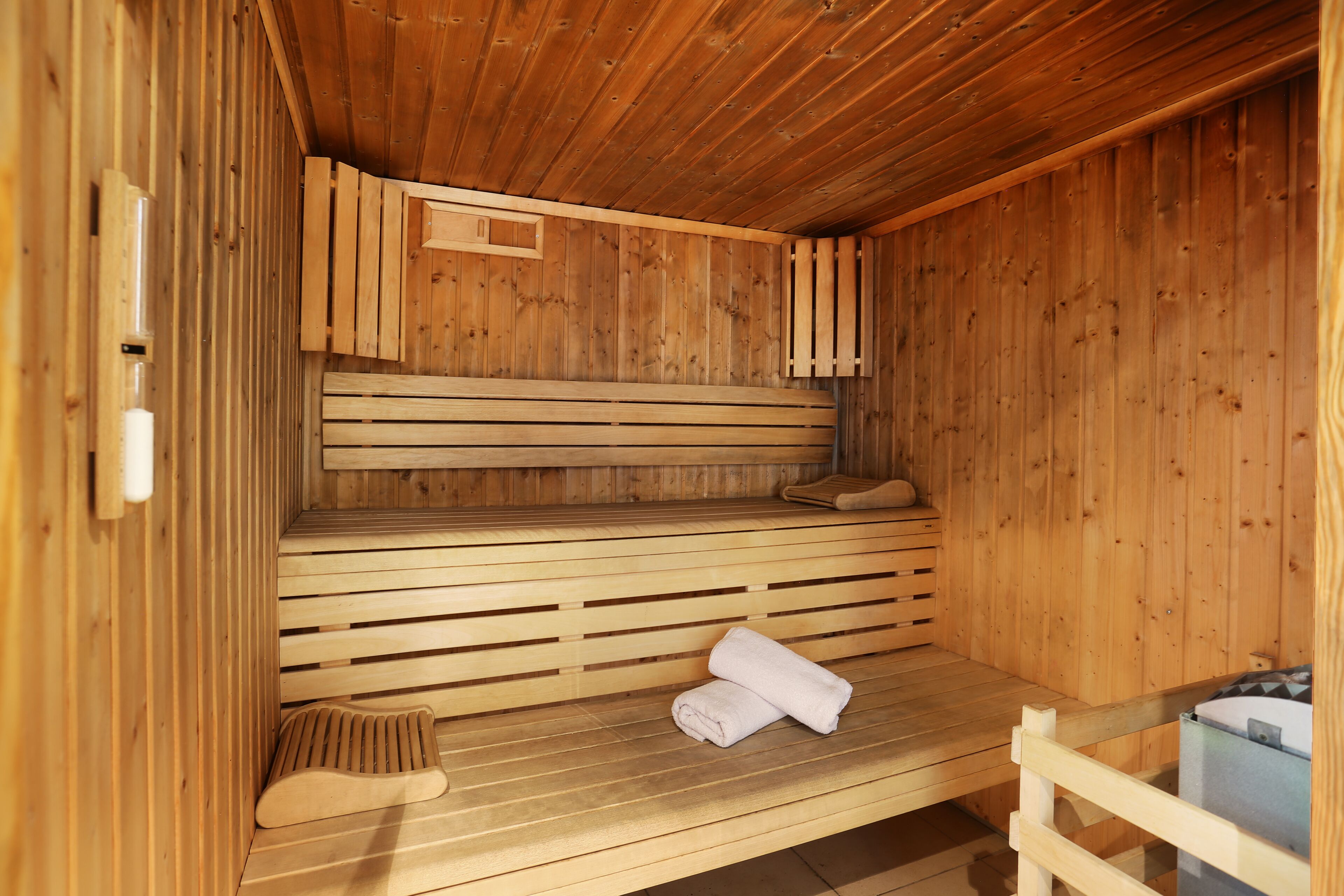 A sauna with wooden benches and a bench with towels.