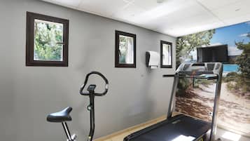 A gym with a treadmill, stationary bike, and a wall-mounted TV.