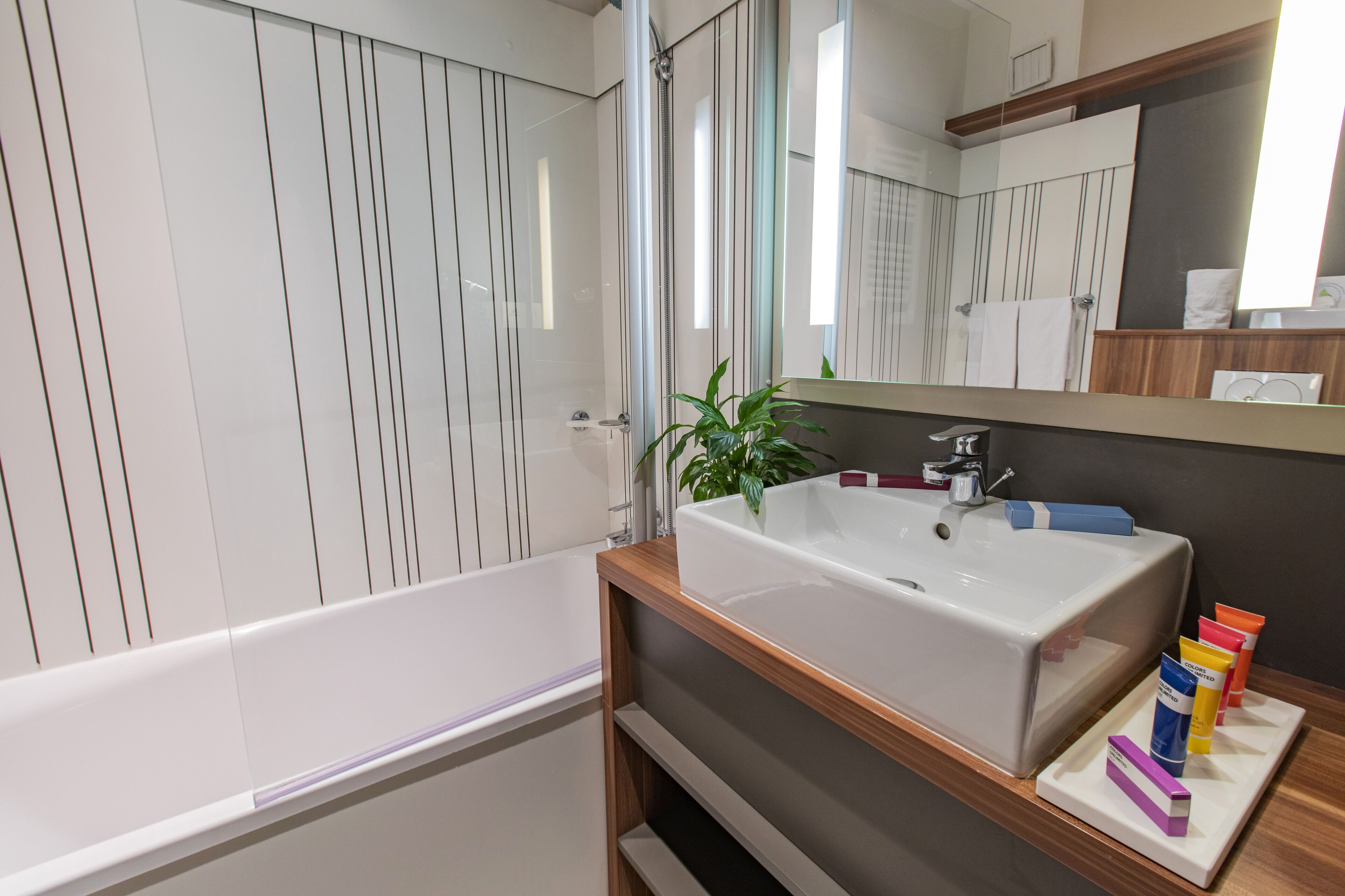 Ein modernes Badezimmer mit einer weißen Badewanne, einem hölzernen Waschtisch mit großem Becken und einem Spiegel darüber.