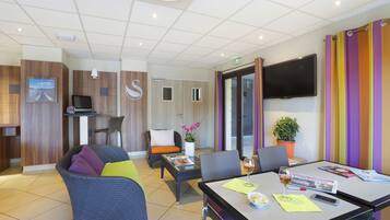 A modern hotel room with a dining area, a TV, and a colorful striped wall.