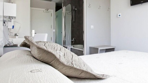 A modern hotel room with a large bed, a bedside table, a mirror, and a TV mounted on the wall. - Alix Boutique (Arteixo)