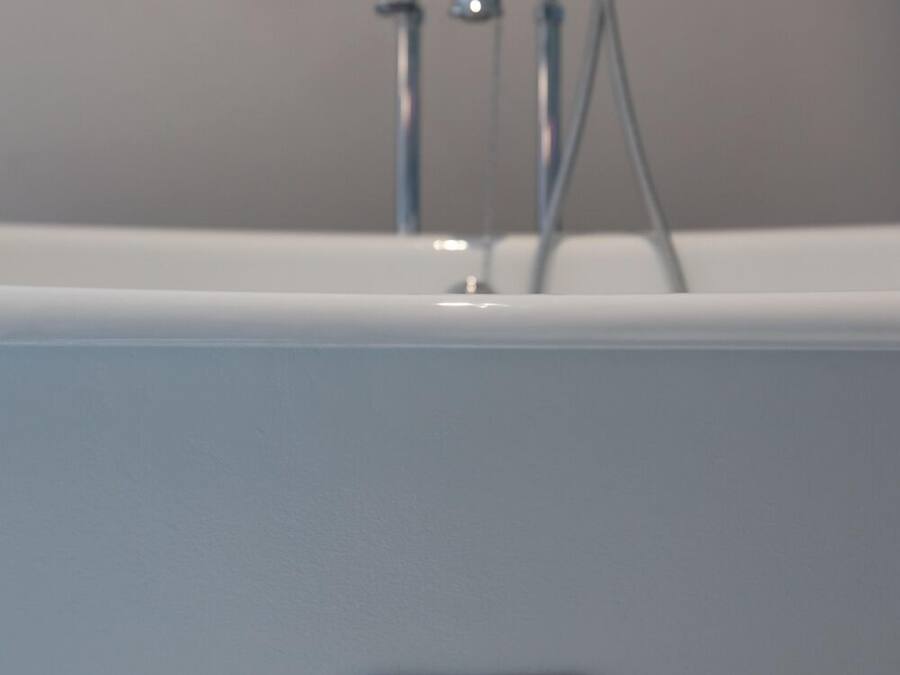 A bathtub with a visible brand name "Roca" and a faucet with water running.
