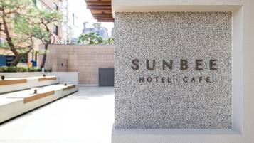 Placa do Sunbee Hotel & Cafe, com design moderno e fachada com textura de pedra.