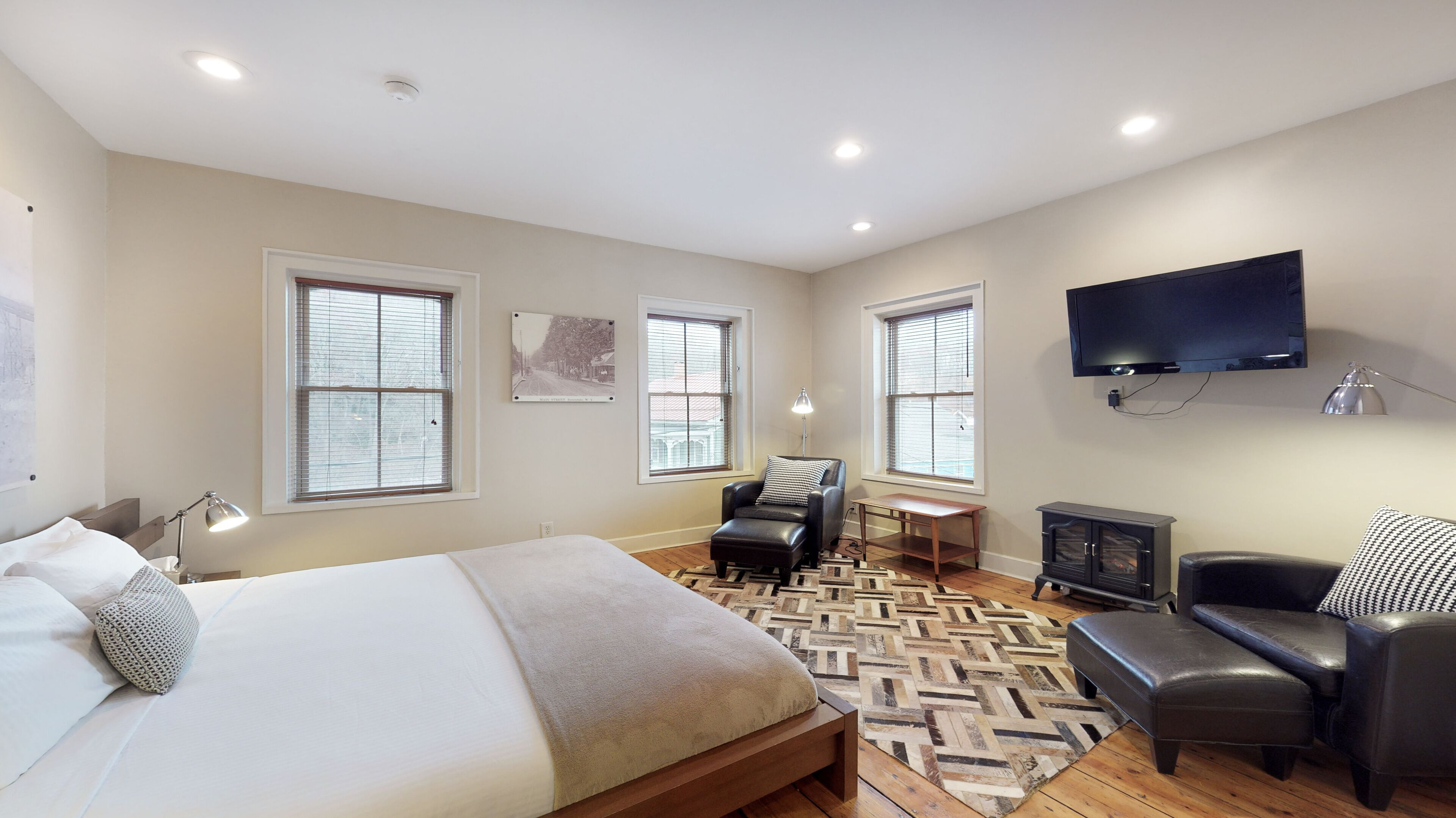 Une chambre moderne avec un grand lit, un bureau, une chaise, une télévision et une cheminée.
