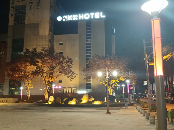 A hotel with a prominent sign, a well-lit entrance, and a fountain in the center.