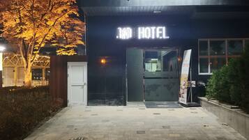 Grand Hotels facade med et markant, oplyst skilt, en lukket indgang og en belagt sti.