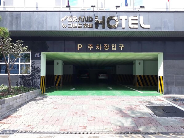 A hotel entrance with a sign reading "GRAND HOTEL" and a parking sign indicating "P" for parking.