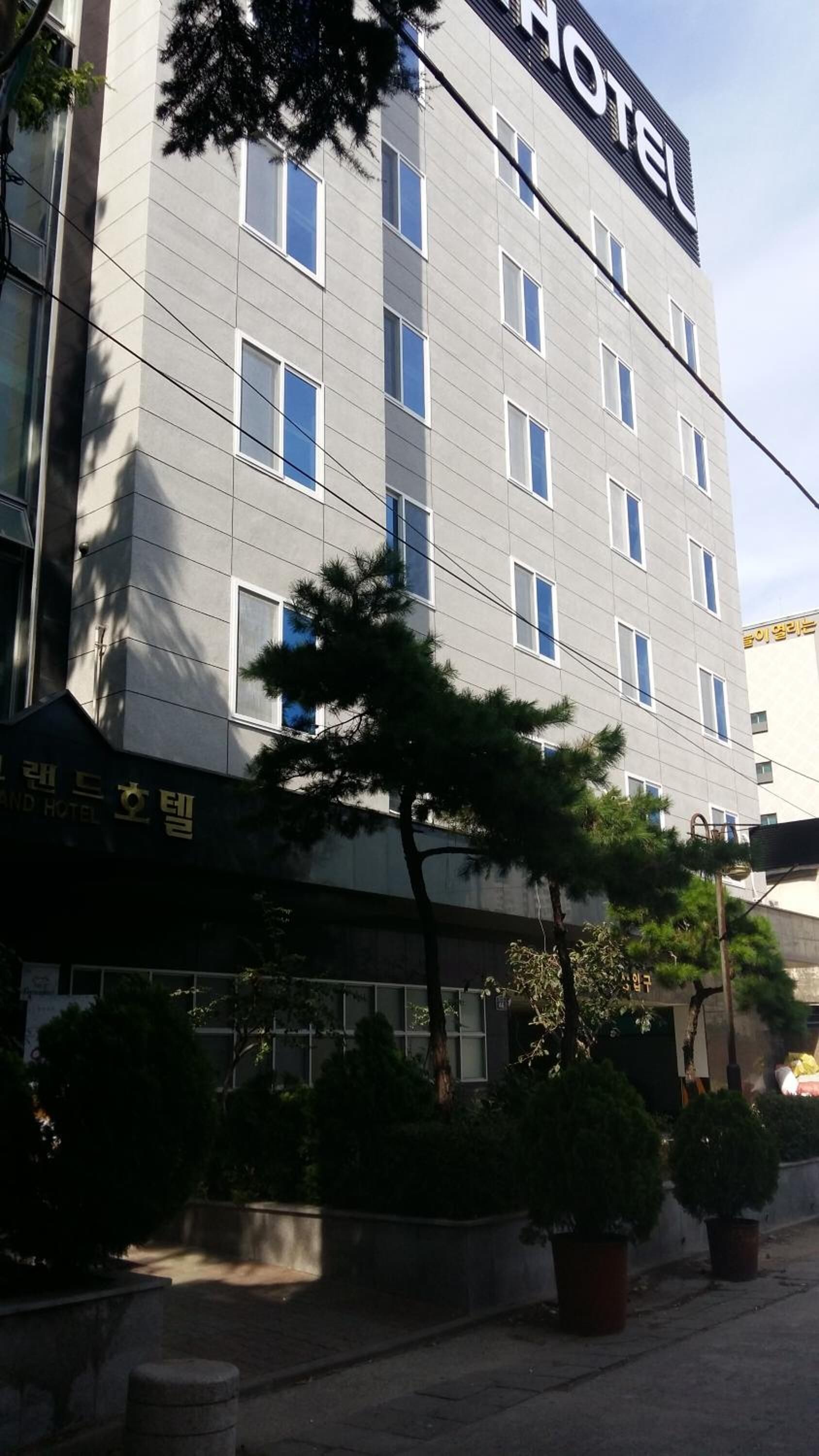 Un hotel de varios pisos con una fachada moderna, que destaca un cartel grande que dice 'HOTEL' en la parte superior.