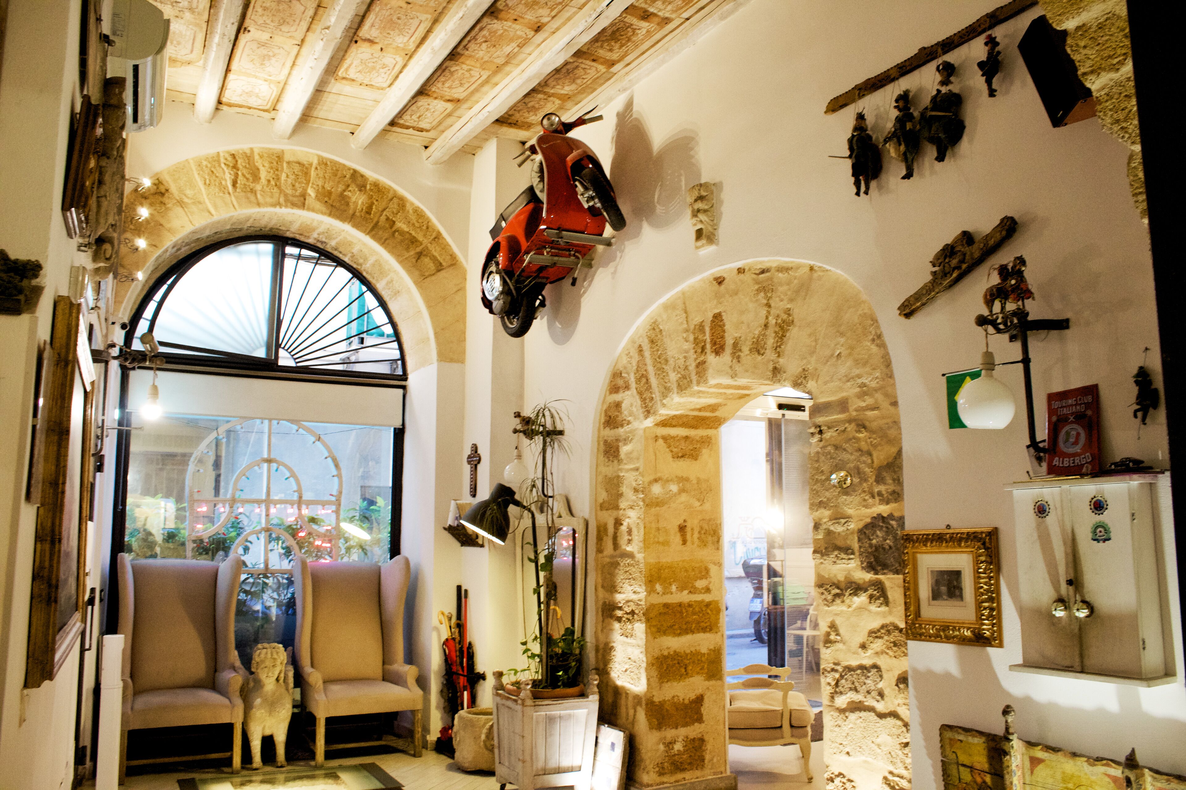 Una habitación con un arco de piedra, una scooter roja y varios adornos, incluyendo un cuadro enmarcado y un aparador.