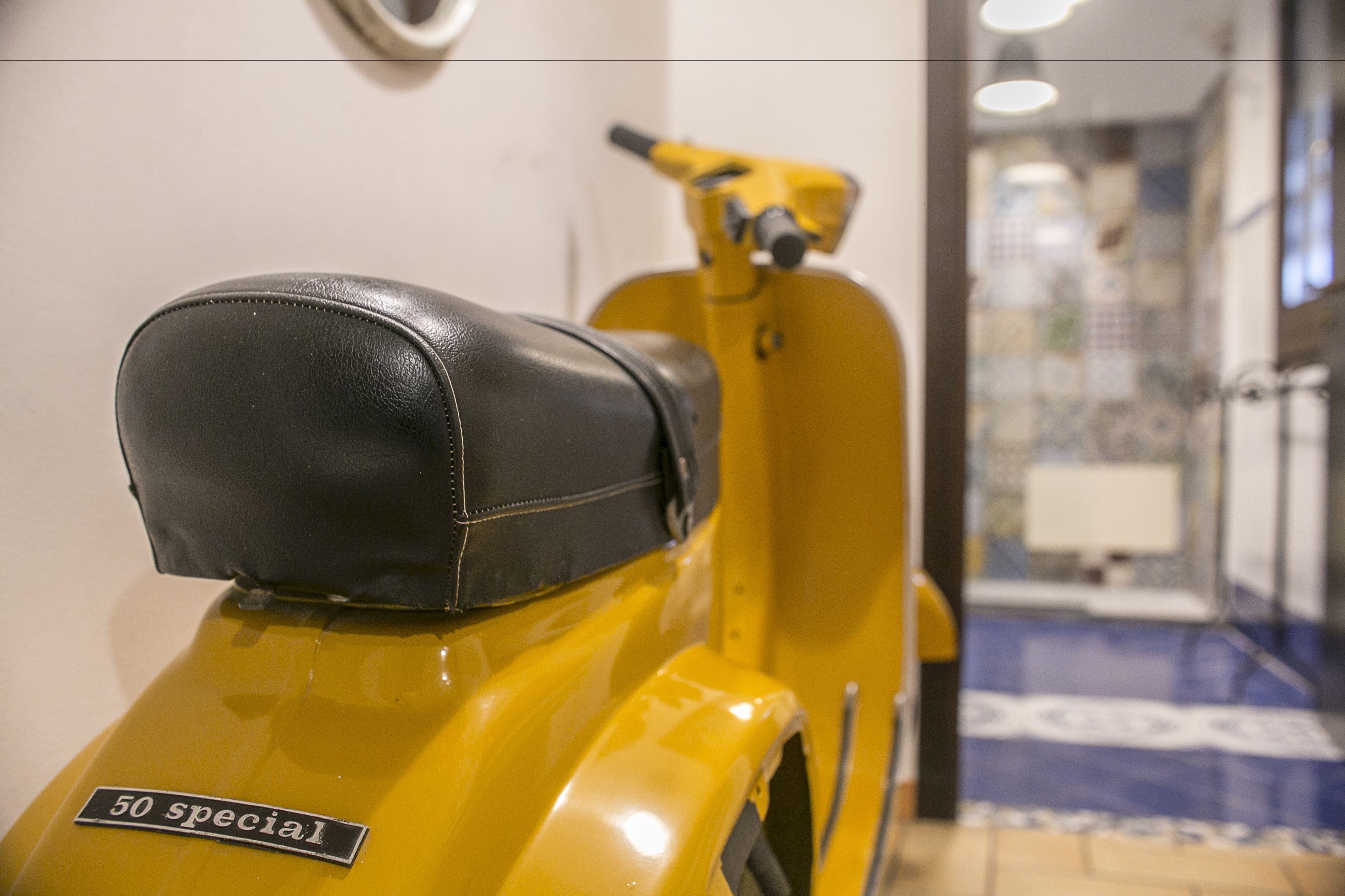 A yellow scooter with a black seat and a sign that reads "50 special."