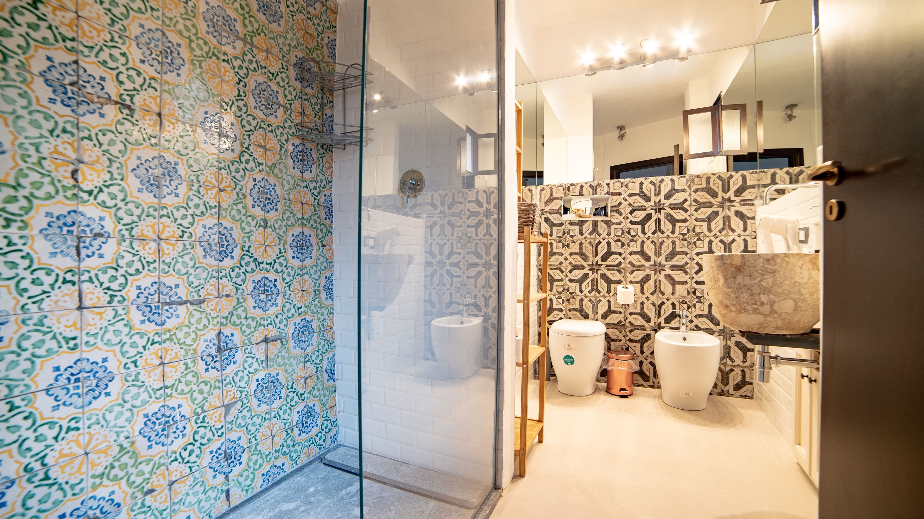 A bathroom with patterned tiles, a glass shower enclosure, and a sink with a marble basin.