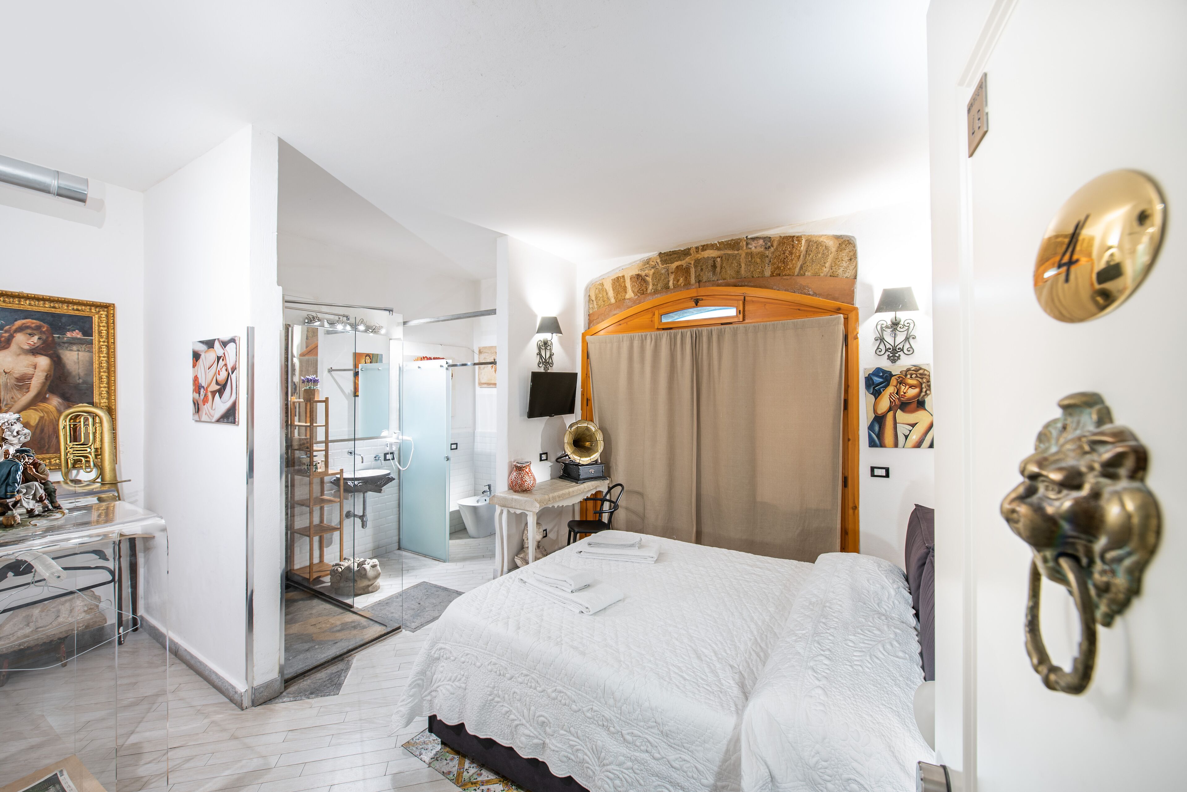Een hotelkamer met een bed, een bureau, een spiegel en een badkamer door een open deur zichtbaar.