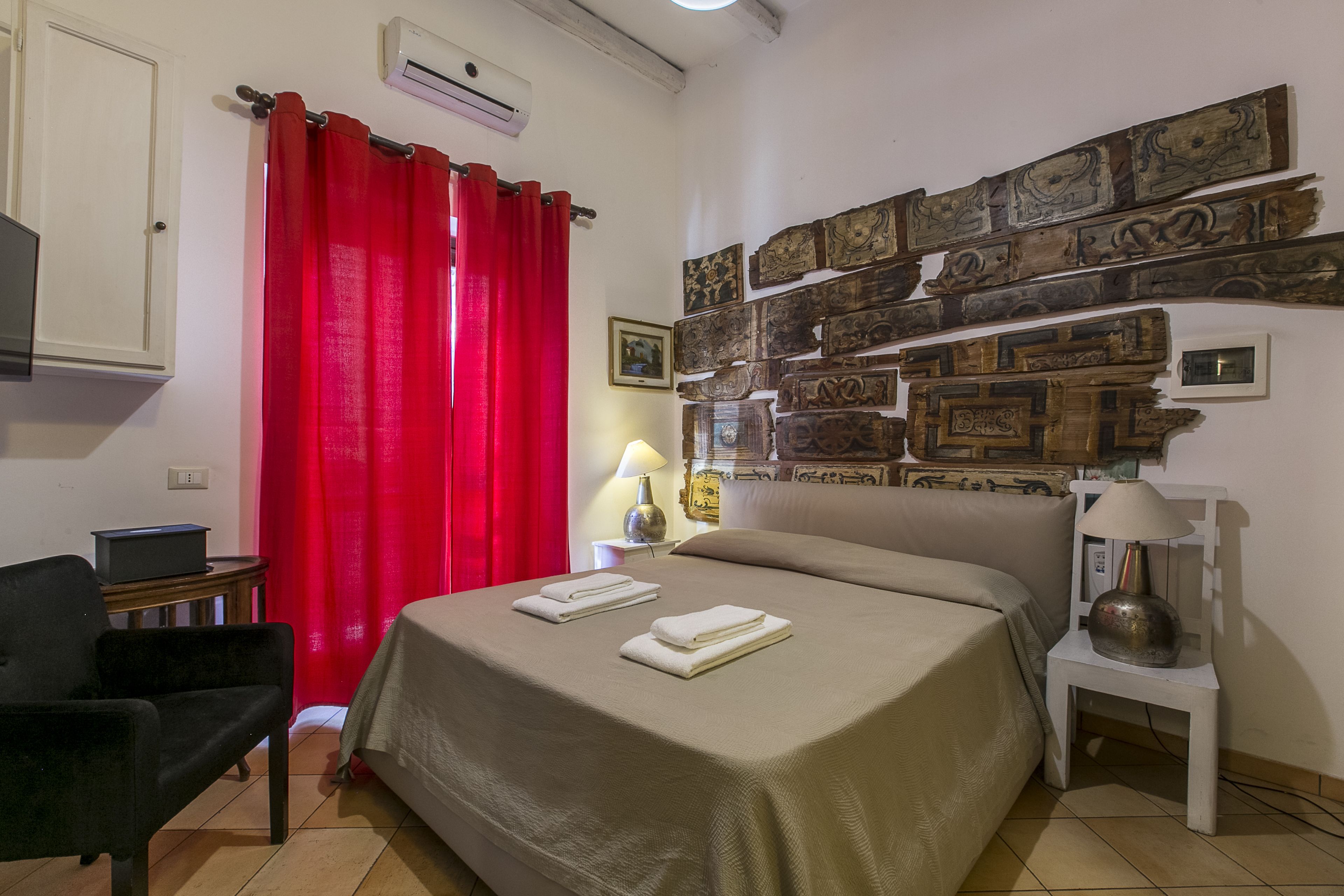 A hotel room with a bed, a chair, a lamp, and a wall decorated with wooden panels.
