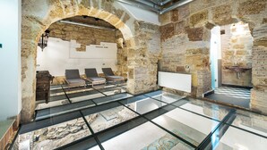 Un interior moderno con arcos de piedra, suelo de cristal y una zona de estar con sillas.