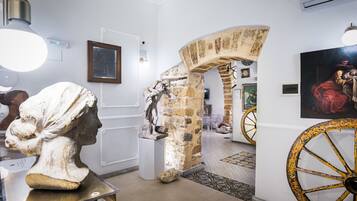 Un interior con un arco de piedra, un busto y una rueda grande y ornamentada.