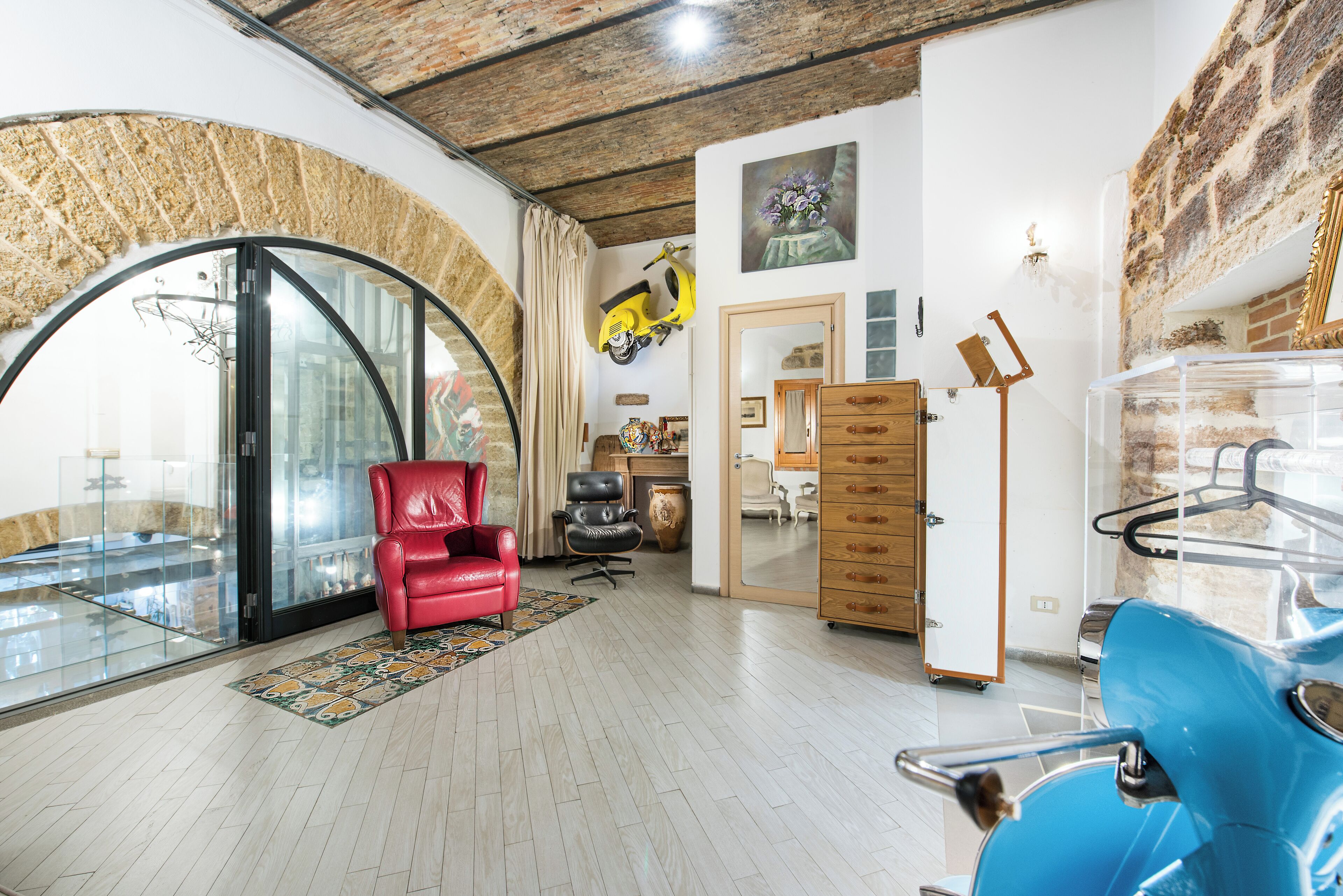 A spacious living area with a red chair, a blue scooter, and a wooden cabinet.