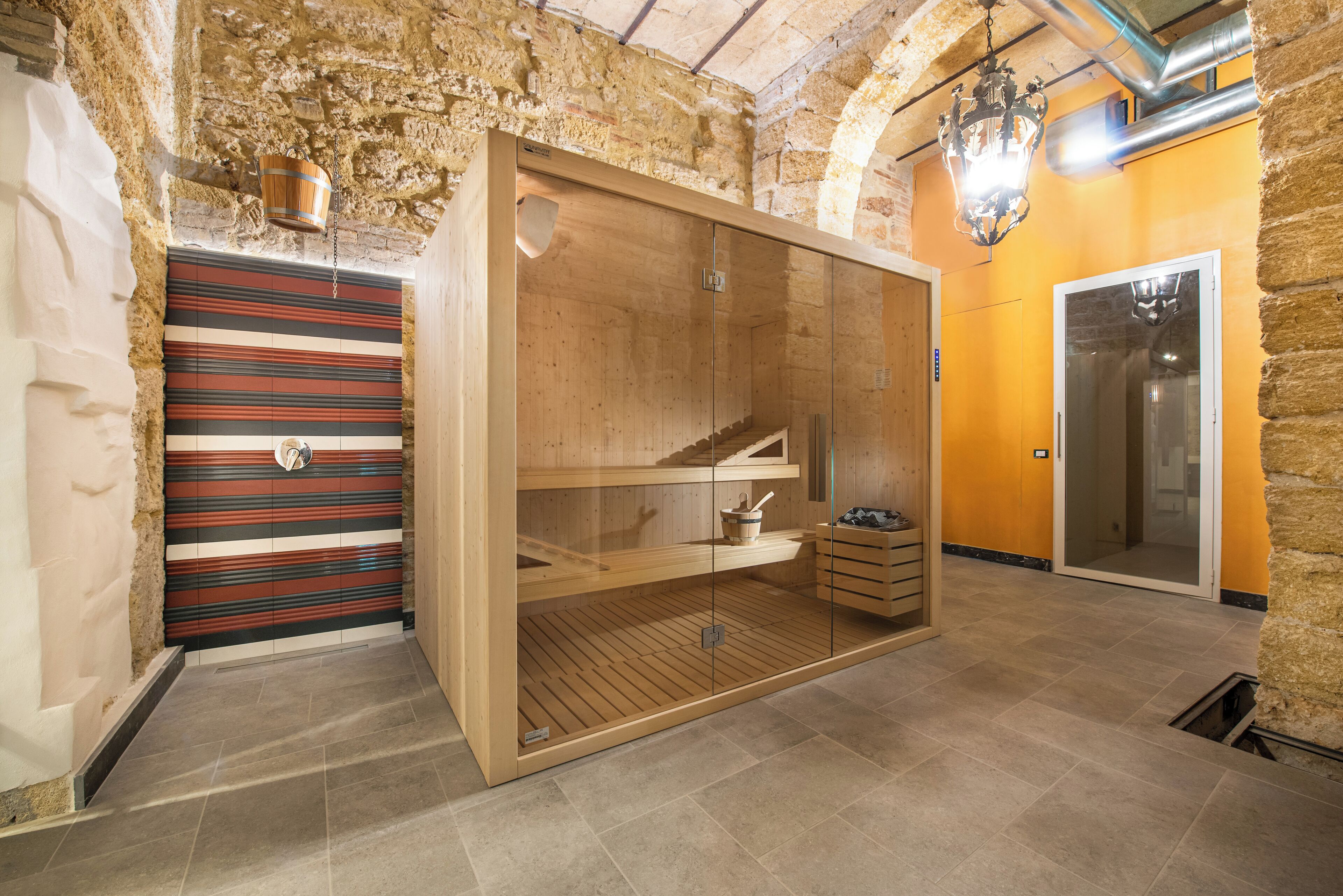 A wooden sauna with glass doors, a striped wall, and a wooden bench.