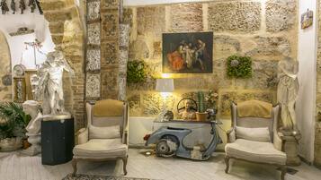 A room with stone walls, two armchairs, a vintage scooter, and various statues and decorations.