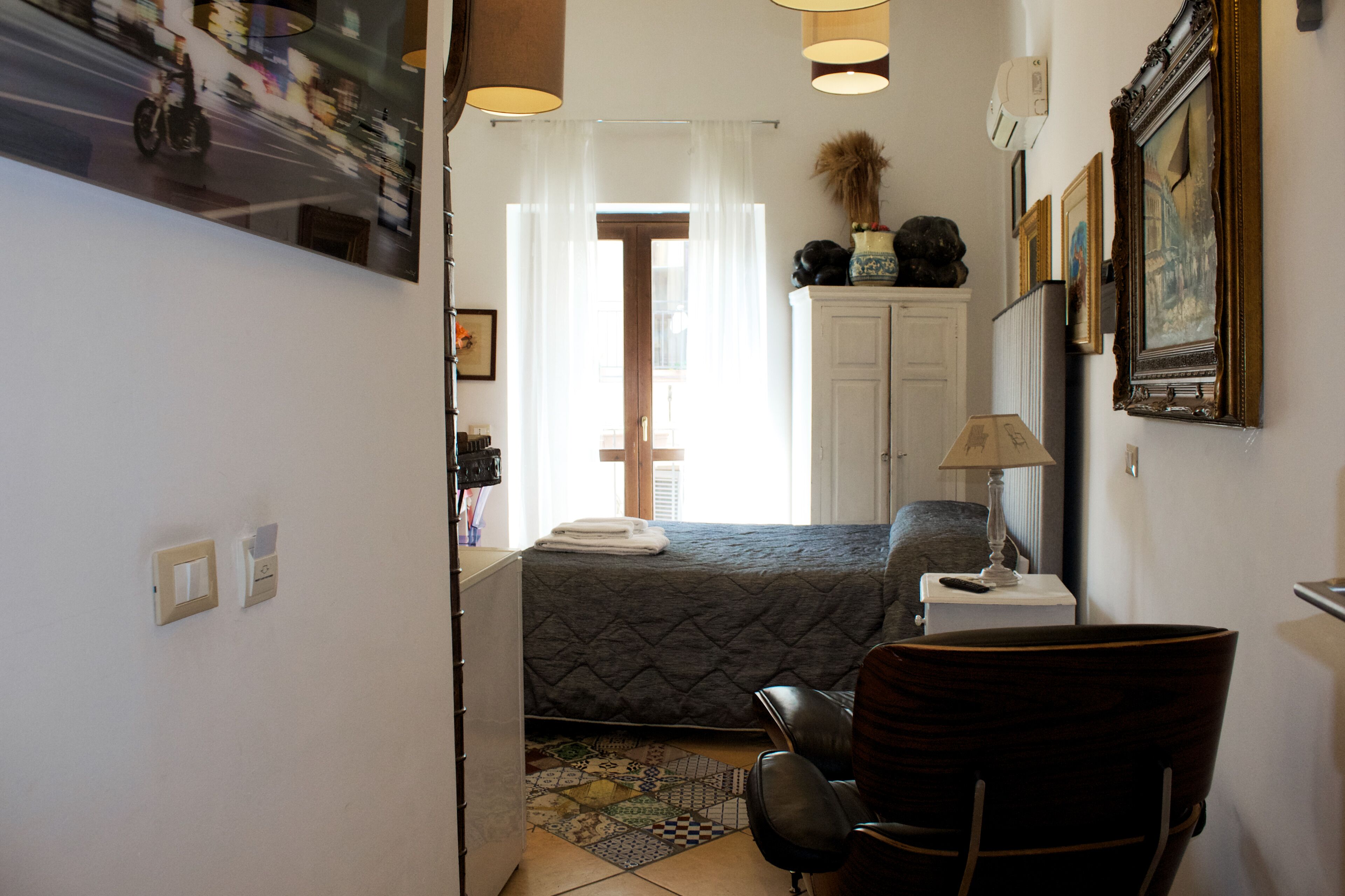 A compact bedroom with a bed, a chair, a desk, and a window with curtains.