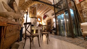 Una habitación con pared de piedra, muebles de madera y un ascensor de vidrio.