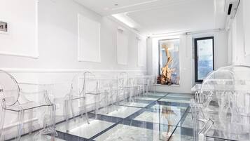 Una sala de conferencias moderna con mesas y sillas de vidrio, piso estampado y un revestimiento de pared de piedra.