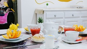 A breakfast table with plates of food, a teapot, cups, and a small plant on a white dresser in the background. - Afea Art & Rooms (Palermo)