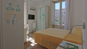 A hotel room with a bed, a desk, a chair, a wardrobe, and a TV. - Afea Art & Rooms (Palermo)