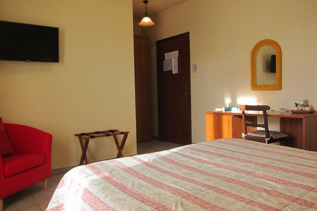 Une chambre à coucher avec un lit, un bureau, une chaise et un fauteuil rouge.
